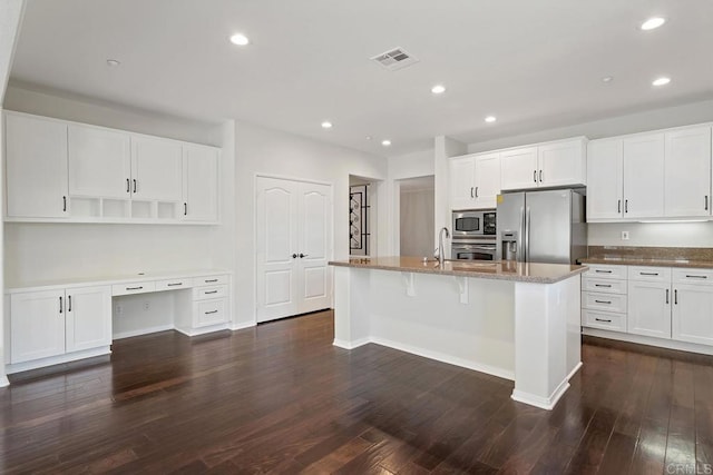 kitchen with light stone countertops, appliances with stainless steel finishes, dark wood-style floors, and built in study area