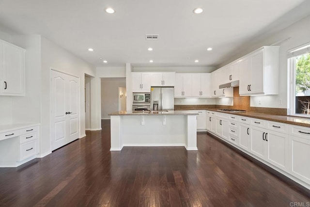 kitchen with dark wood-style floors, visible vents, white cabinets, under cabinet range hood, and appliances with stainless steel finishes