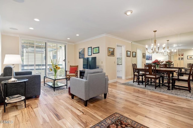 living area featuring an inviting chandelier, baseboards, light wood-style floors, and ornamental molding