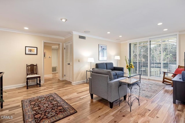 living room with baseboards, light wood-style floors, visible vents, and ornamental molding