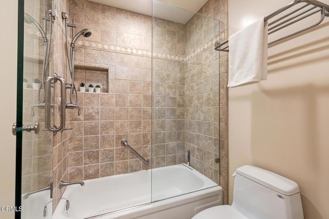 bathroom with toilet and bath / shower combo with glass door