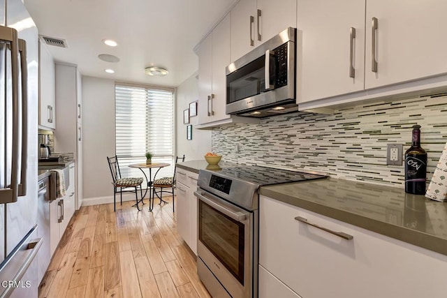 kitchen with visible vents, stainless steel appliances, light wood-style floors, dark countertops, and tasteful backsplash