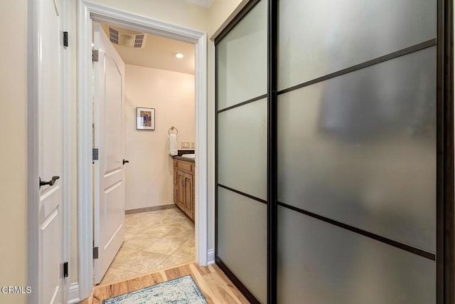 bathroom with visible vents, vanity, baseboards, and wood finished floors