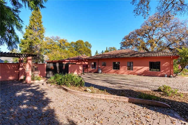 rear view of property with a tiled roof, a patio, and fence