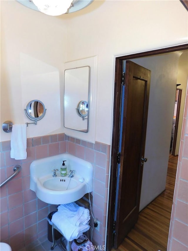 bathroom featuring wainscoting, tile walls, and wood finished floors