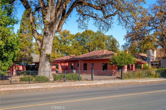 view of front of house with a fenced front yard, stucco siding, and a tile roof