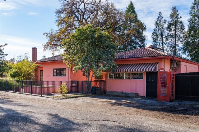 view of front of property featuring a chimney, stucco siding, a tile roof, and fence