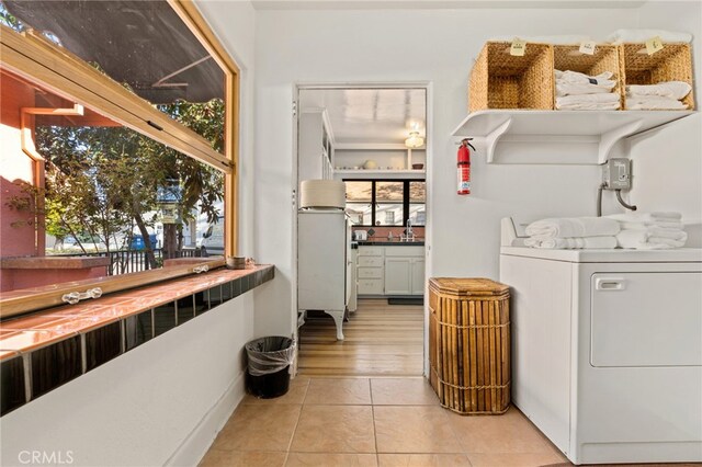 laundry area with light tile patterned floors, laundry area, washer / dryer, and a sink