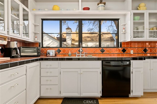 kitchen with a sink, black dishwasher, white cabinetry, tile countertops, and a toaster