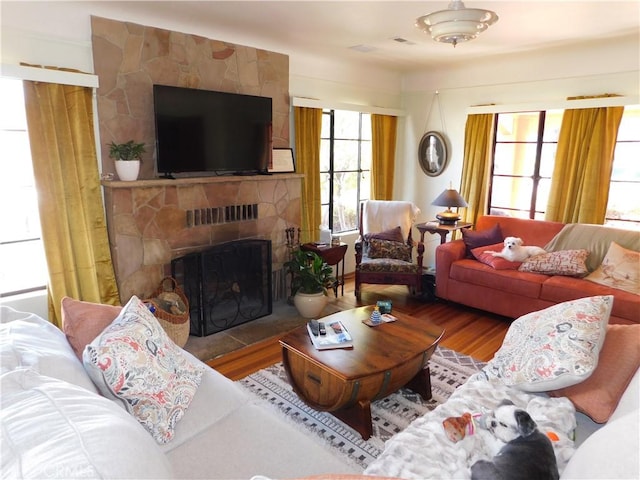 living area with a stone fireplace and wood finished floors