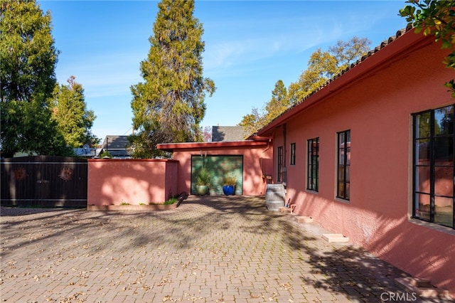 view of side of property with stucco siding and fence