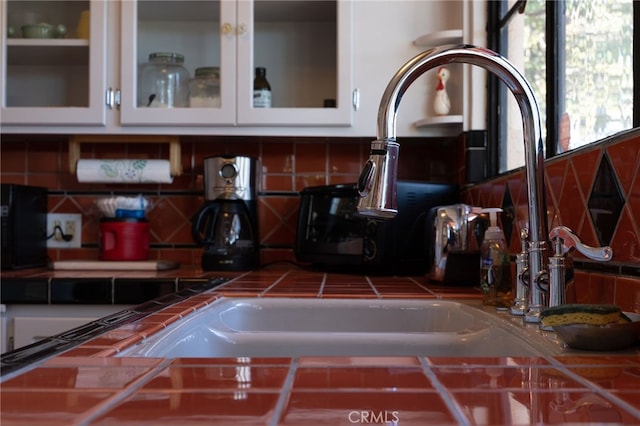 interior space featuring tasteful backsplash, white cabinetry, and tile counters