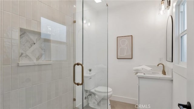 bathroom featuring vanity, a shower stall, toilet, and baseboards