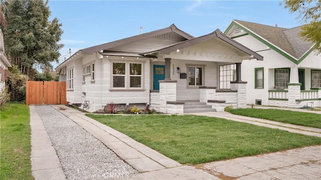 bungalow-style house with covered porch, a front yard, and fence