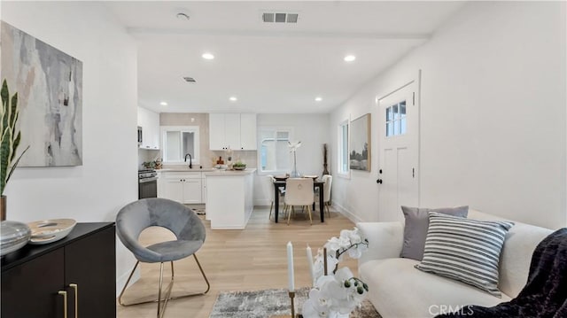 living room with recessed lighting, visible vents, light wood-style flooring, and baseboards