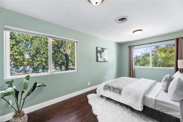 bedroom with visible vents, baseboards, and wood finished floors