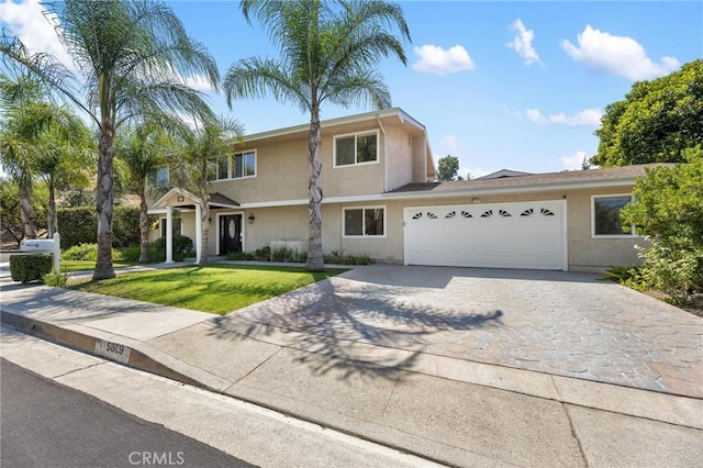 view of front of home featuring stucco siding, driveway, a front lawn, and a garage