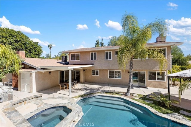 back of house featuring a patio, an in ground hot tub, stucco siding, a chimney, and central air condition unit