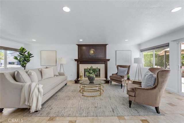 living room featuring a tiled fireplace, recessed lighting, and baseboards