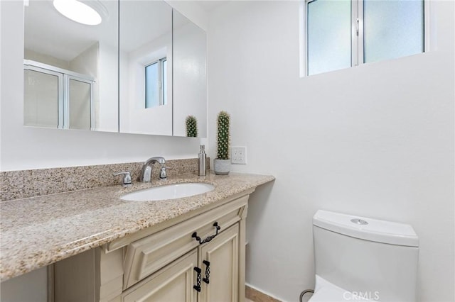 full bath featuring toilet, a shower stall, and vanity