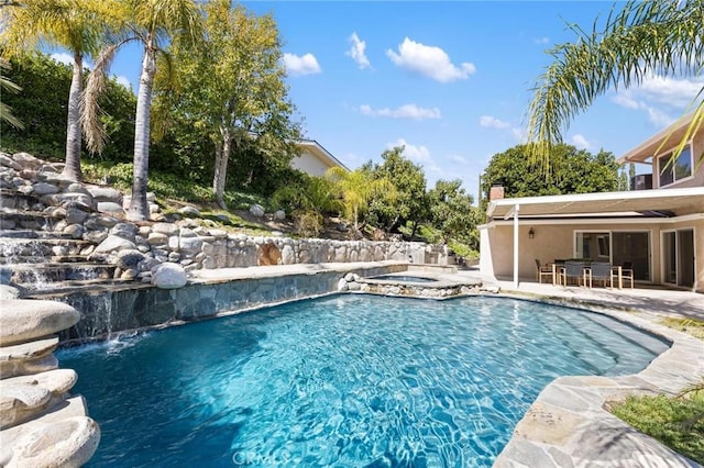 outdoor pool with a patio and an in ground hot tub