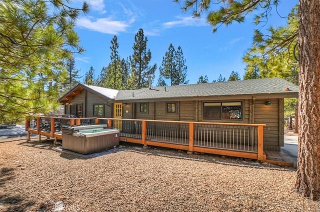 rear view of property featuring a wooden deck and a hot tub