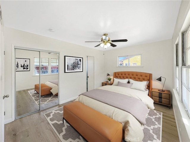 bedroom with baseboards, multiple windows, a ceiling fan, and light wood-style floors