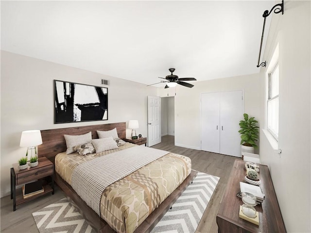 bedroom featuring visible vents, baseboards, ceiling fan, light wood-style flooring, and a closet