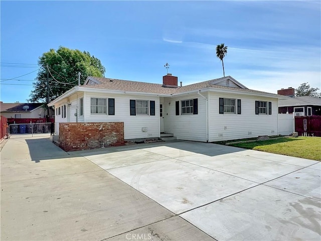 view of front of property with a front lawn, fence, driveway, and a chimney