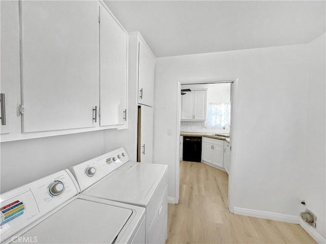 washroom with light wood-style flooring, washer and clothes dryer, a sink, cabinet space, and baseboards