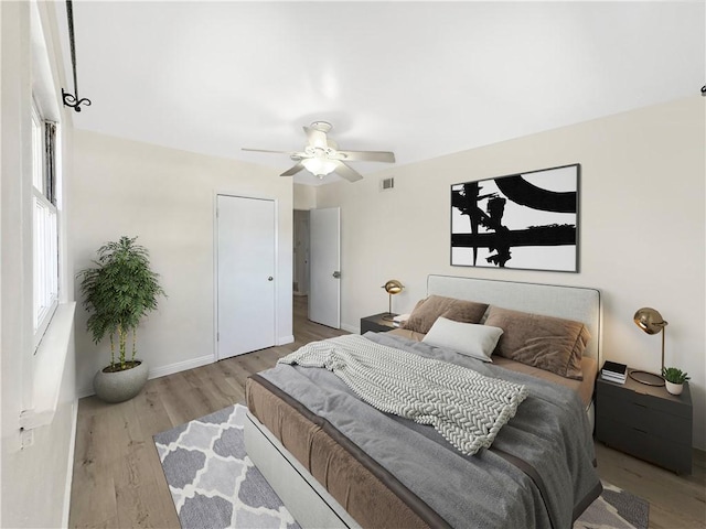 bedroom with ceiling fan, wood finished floors, visible vents, and baseboards