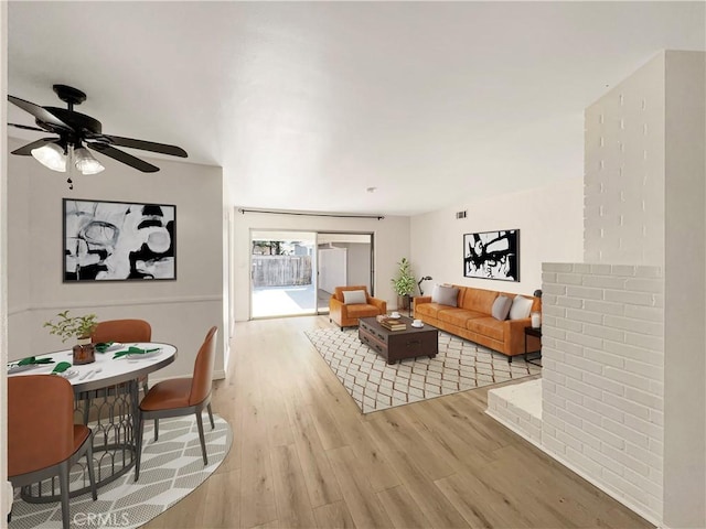 living area with wood finished floors and a ceiling fan