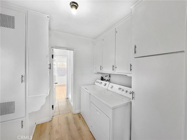 laundry room featuring cabinet space, washing machine and dryer, light wood-type flooring, and visible vents