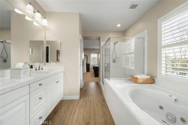 bathroom featuring vanity, wood finished floors, visible vents, a shower stall, and a jetted tub