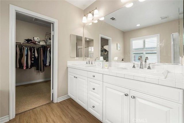 bathroom with wood finished floors, visible vents, and a sink