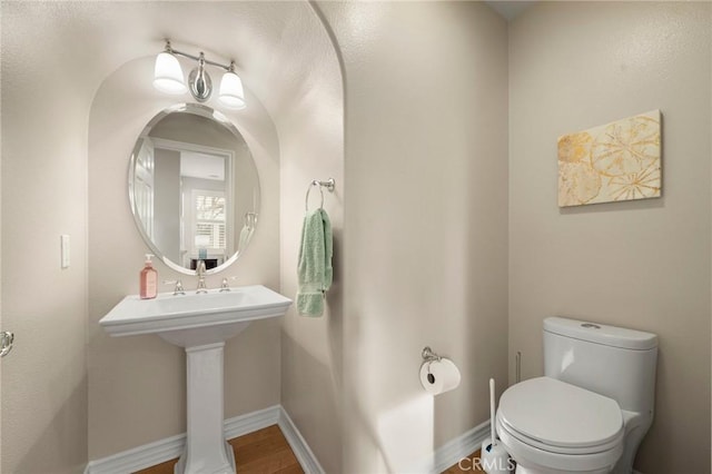 bathroom with a sink, baseboards, toilet, and wood finished floors