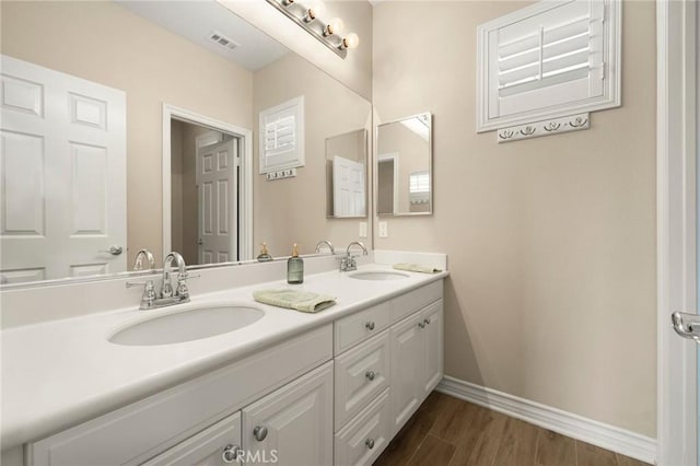 bathroom with baseboards, wood finished floors, visible vents, and a sink