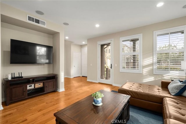 living room with light wood-type flooring, visible vents, baseboards, and recessed lighting