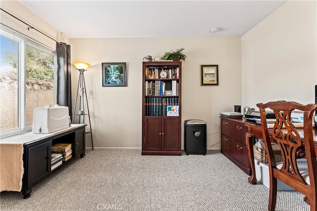 office space with baseboards and light carpet