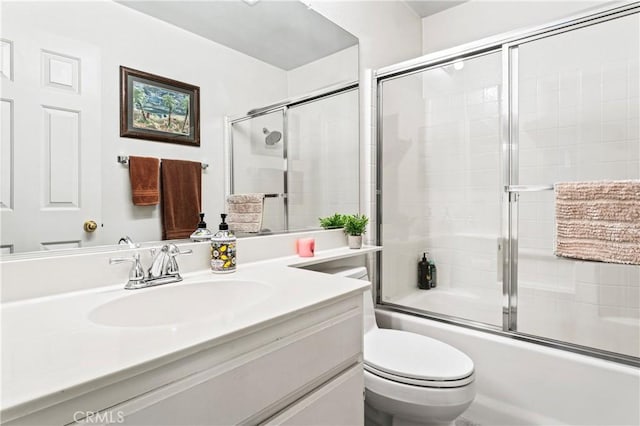 full bath featuring toilet, vanity, and shower / bath combination with glass door