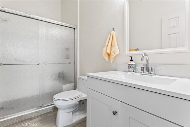 full bath featuring vanity, toilet, wood finished floors, and a shower with shower door