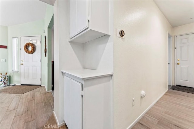 foyer with baseboards and light wood-style floors