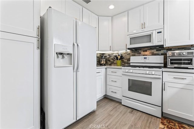 kitchen featuring white appliances, light wood-style floors, white cabinets, a toaster, and decorative backsplash