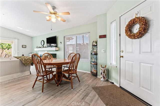 dining area with light wood finished floors, plenty of natural light, baseboards, and vaulted ceiling