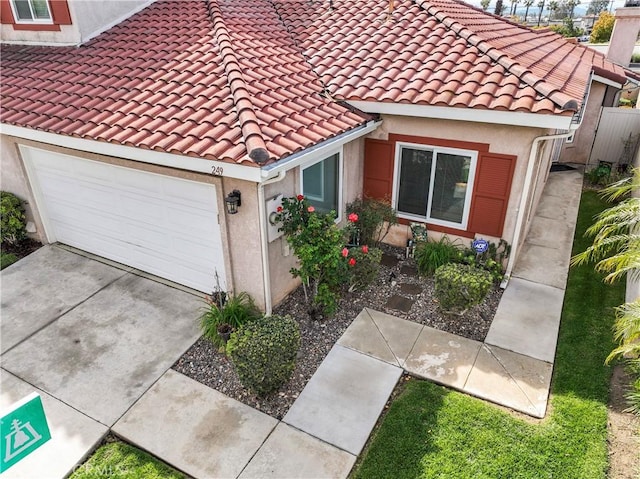 view of front of house with stucco siding, a tiled roof, an attached garage, and driveway