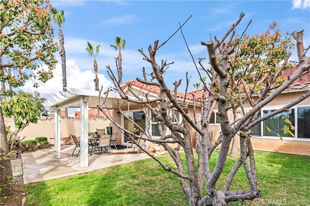 back of house with fence, a tiled roof, stucco siding, a lawn, and a patio area