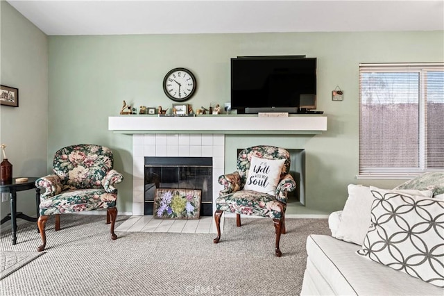 carpeted living area with a tiled fireplace