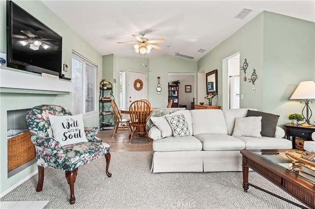 living area featuring visible vents, a ceiling fan, lofted ceiling, and wood finished floors