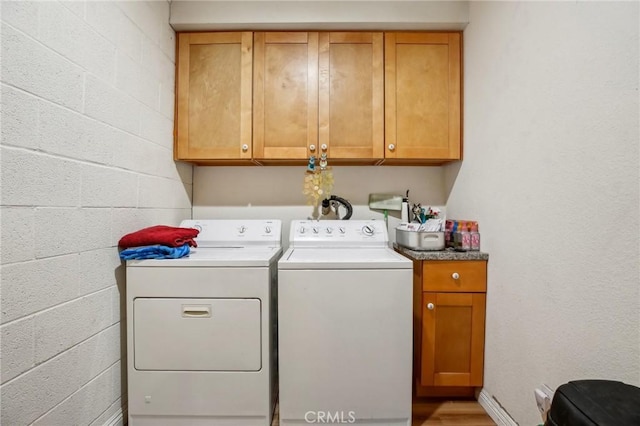 laundry room with washer and clothes dryer, cabinet space, and concrete block wall