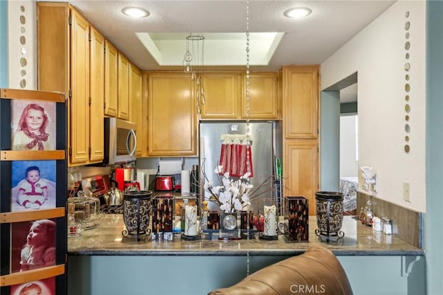 kitchen with stone counters, a textured ceiling, appliances with stainless steel finishes, and a peninsula